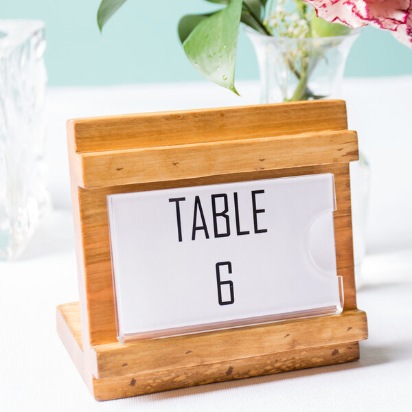 A wooden Cal-Mil Madera displayette with a table number and a flower in a vase.