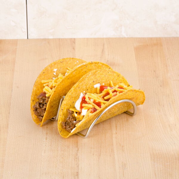 A group of tacos on a stainless steel Cal-Mil taco holder with meat and cheese.
