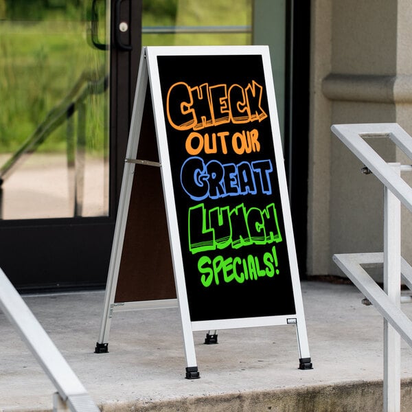 An Aarco aluminum A-Frame sign with black marker board displaying "Check out our great lunch specials" on a sidewalk.