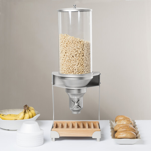 A Cal-Mil wooden cereal dispenser with a cylinder of cereal in it.