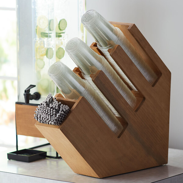 A wooden Cal-Mil countertop organizer with plastic cups and straws.