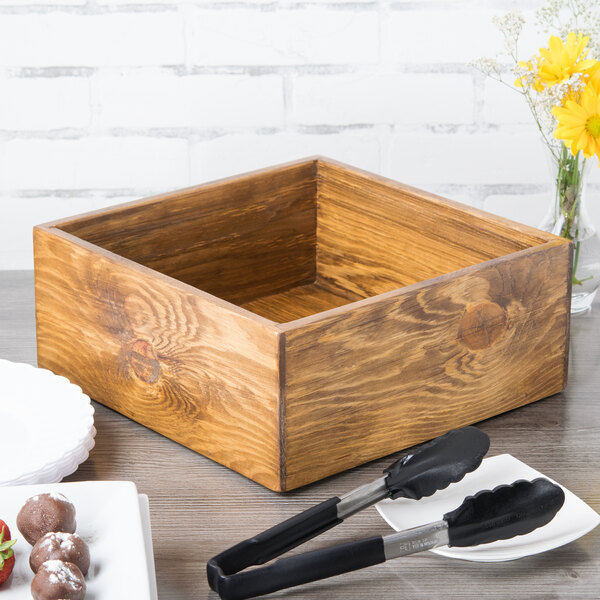 A Cal-Mil rustic pine cooling base on a table with tongs in a wooden box.
