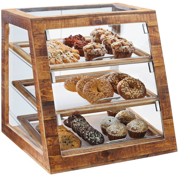 A Cal-Mil Madera rustic pine bakery display case on a counter filled with pastries, muffins, and bagels.