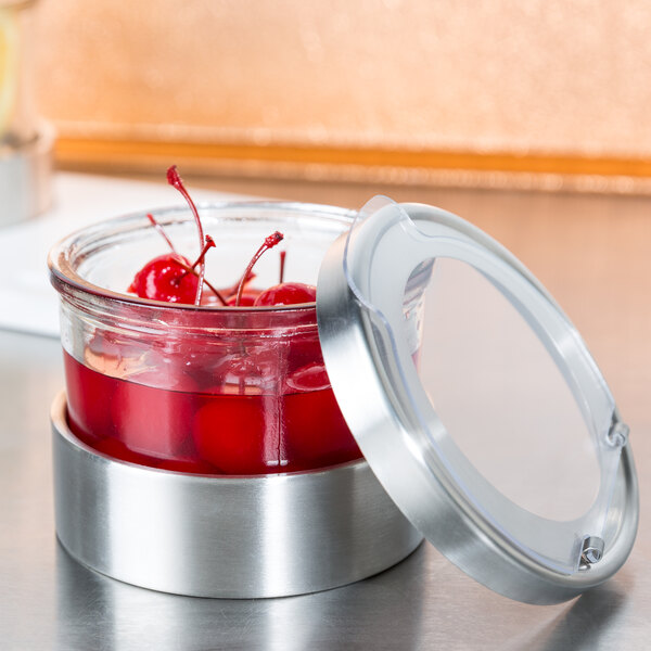 A Cal-Mil Luxe jar filled with red cherries and liquid on a kitchen counter.