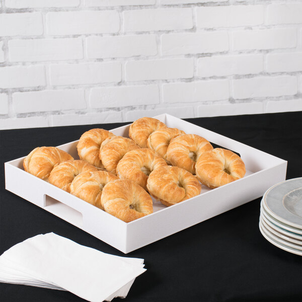 A white Cal-Mil plastic room service tray with pastries and plates on it.