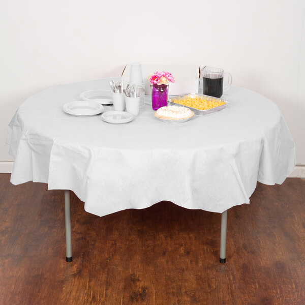 A white Creative Converting OctyRound table cover on a table with food, plates, cups, and bowls.