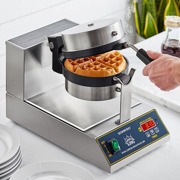 A person using a Carnival King non-stick Belgian waffle maker to cook waffles.