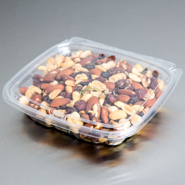 A Dart clear plastic deli container of mixed nuts with a flat lid.