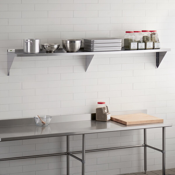 A Regency stainless steel wall shelf holding food items.