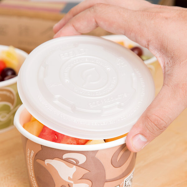 A hand holding an Eco-Products plastic lid over a cup of fruit.
