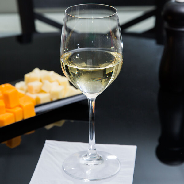 A Spiegelau Vino Grande white wine glass on a table with a glass of white wine.