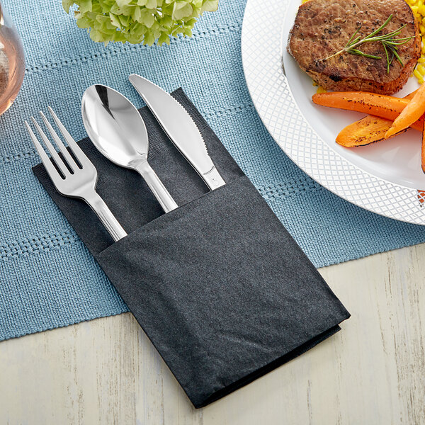 A Visions plastic cutlery set with a fork, knife and napkin on a plate of food.