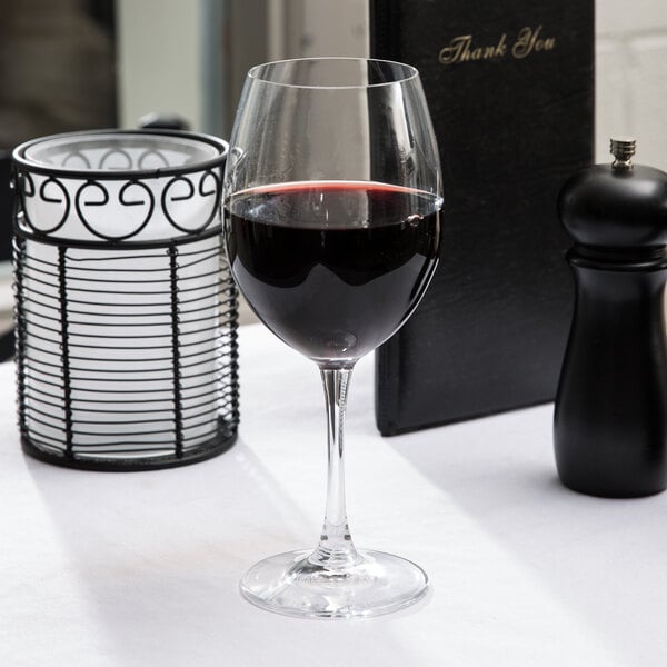 A Spiegelau Bordeaux wine glass with red wine on a table.