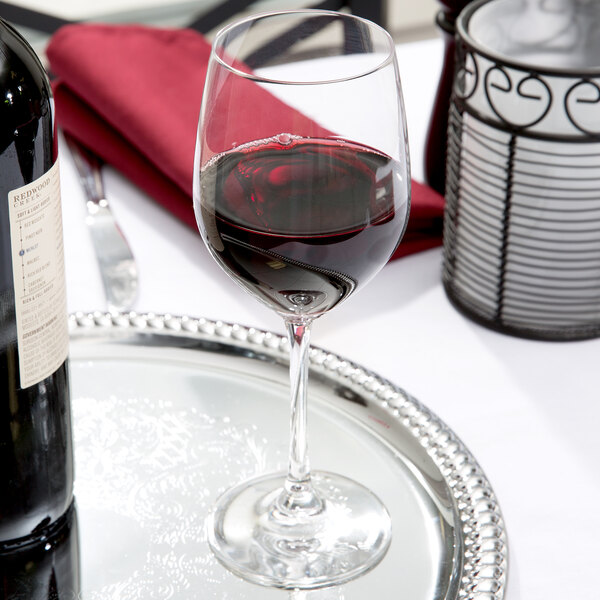 A Spiegelau Vino Grande red wine glass on a silver tray with a bottle of wine.