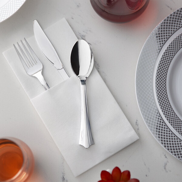 A Visions heavy weight silver plastic fork and knife on a white napkin on a table.