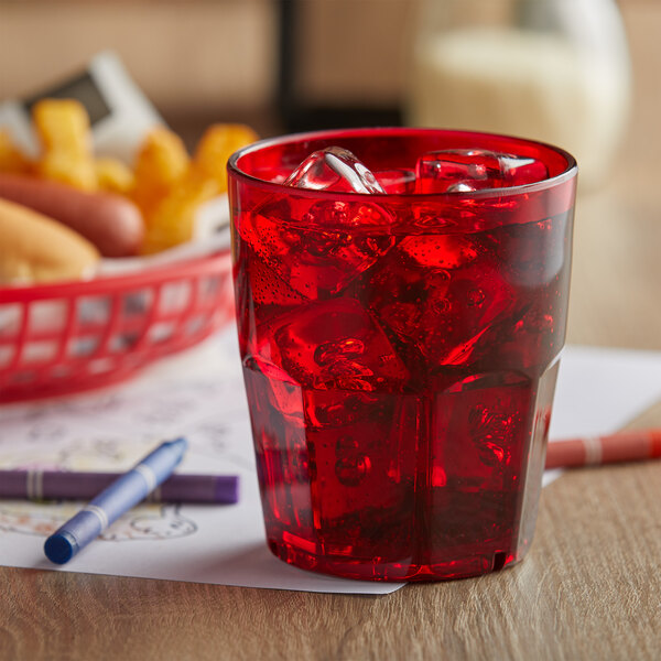 A red GET Bahama plastic tumbler filled with ice and a red drink on a table with a red basket of food.