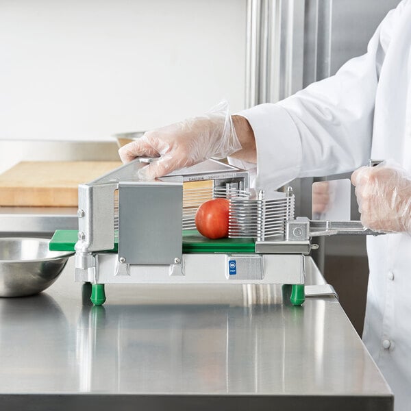 A person in white gloves and a white coat using a Garde 3/16" Tomato Slicer to cut a tomato.