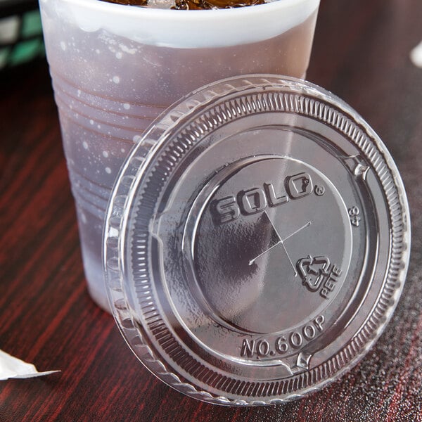 A Solo plastic cup with a clear plastic lid and a straw slot on a table.