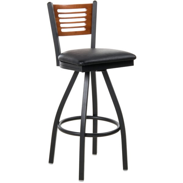 A BFM Seating black metal bar stool with a cherry wood back and black vinyl seat.