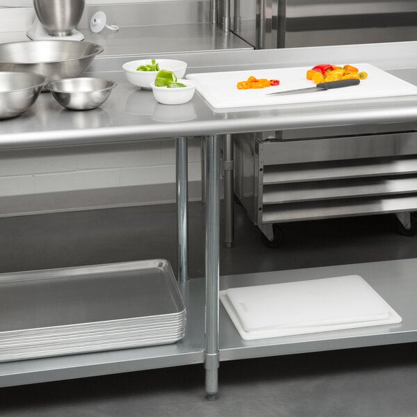 A Steelton stainless steel work table with undershelf and a cutting board with bowls and a knife on it.