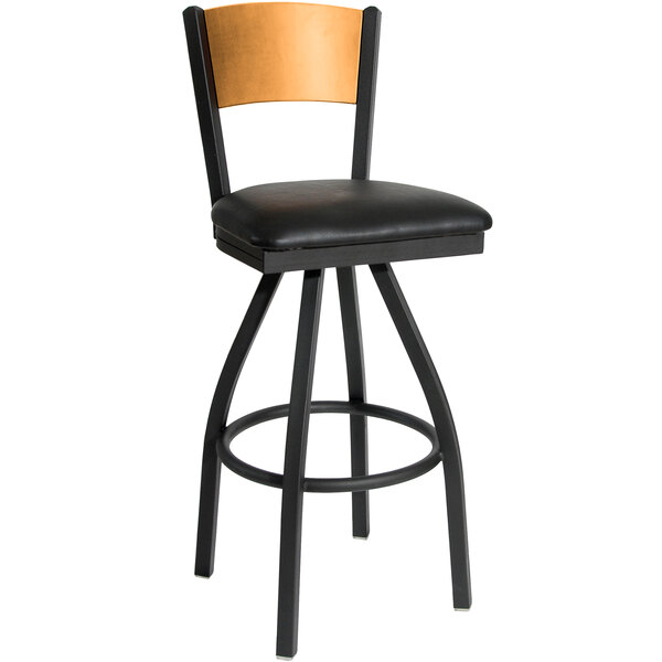 A black metal swivel bar stool with a wooden back and black vinyl seat.