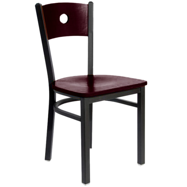 A BFM Seating black metal side chair with a mahogany wooden back and seat with a hole in the back.