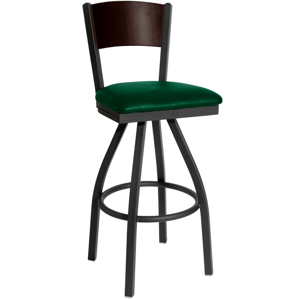 A BFM Seating bar height chair with a green vinyl seat and black metal frame with a walnut finish wooden back.
