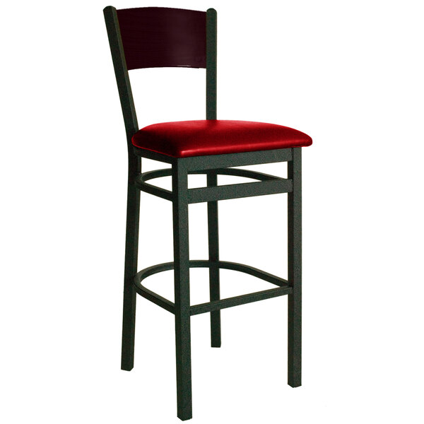 A BFM Seating black metal bar chair with a mahogany wooden back and red vinyl seat.