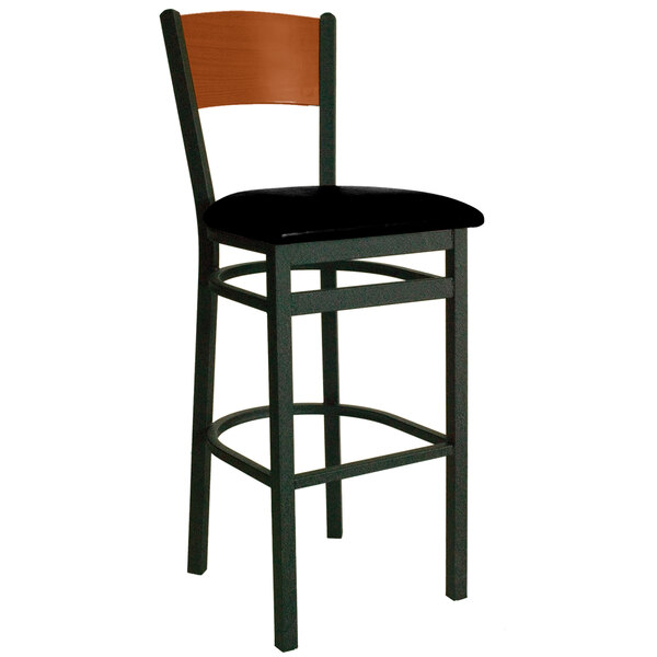 A BFM Seating black metal bar stool with a cherry finish wooden back and black vinyl seat.