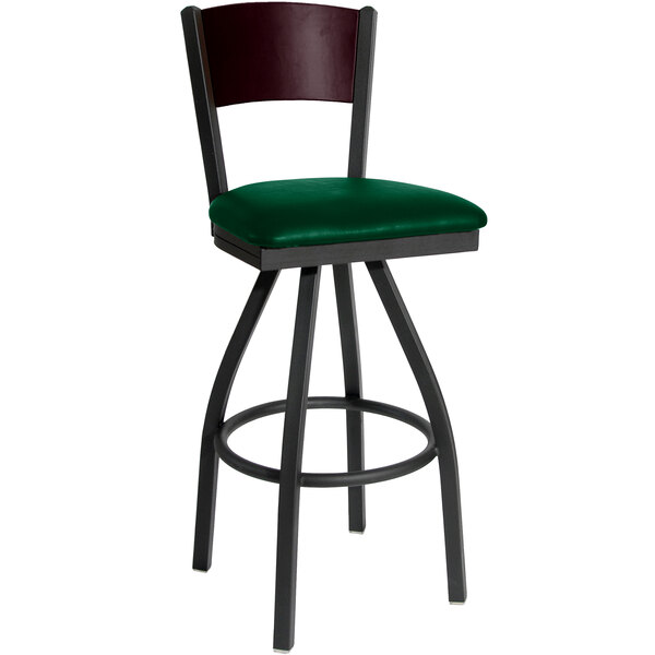 A BFM Seating black metal swivel restaurant bar stool with a green vinyl seat.