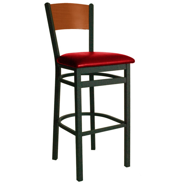 A BFM Seating black metal bar chair with red vinyl seat and cherry finish wooden back.