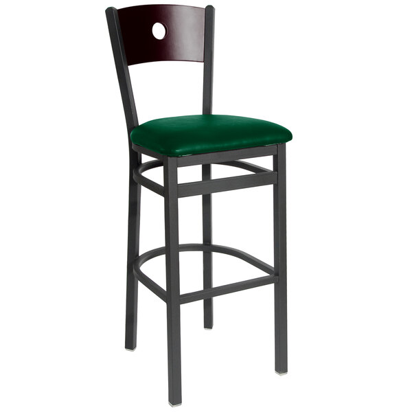 A BFM Seating black metal bar height chair with mahogany wooden back and green vinyl seat.