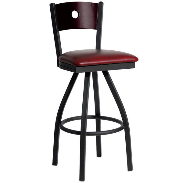 A BFM Seating black metal bar stool with mahogany wooden back and burgundy vinyl swivel seat.