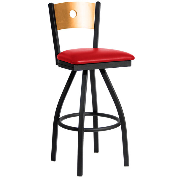 A black metal BFM Seating bar stool with a natural wooden back and red vinyl swivel seat.