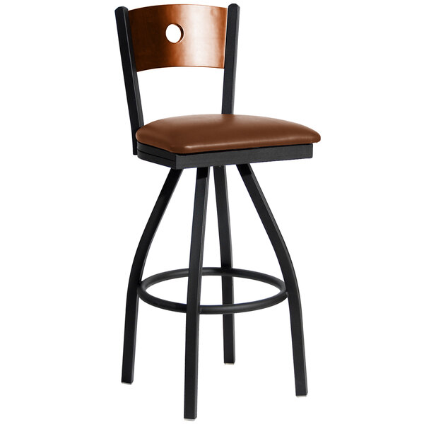 A BFM Seating black metal bar stool with a cherry wood back and light brown vinyl seat.