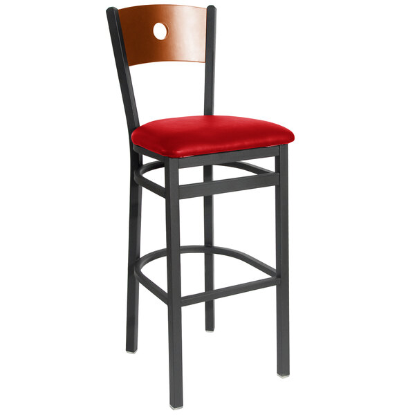 A black metal BFM Seating bar stool with a red vinyl seat and cherry wood back.