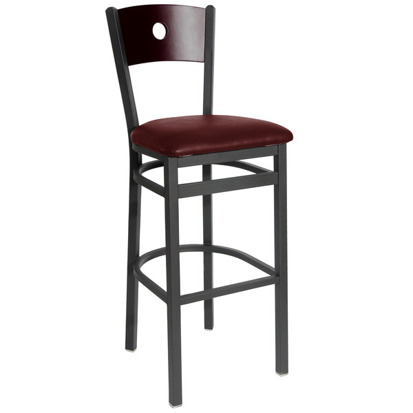 A BFM Seating black metal bar stool with mahogany back and burgundy vinyl seat.