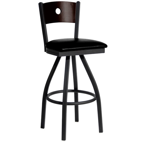 A BFM Seating black metal bar stool with a black vinyl seat and walnut back.