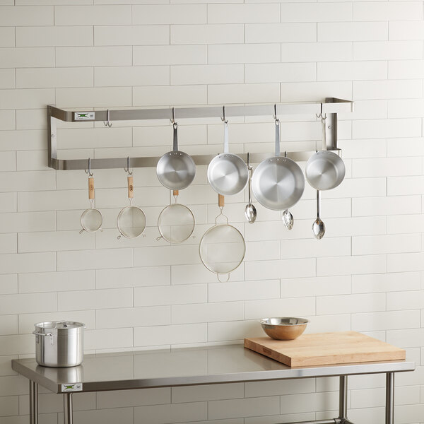 A kitchen with Regency stainless steel wall mounted pot rack holding pots and pans.