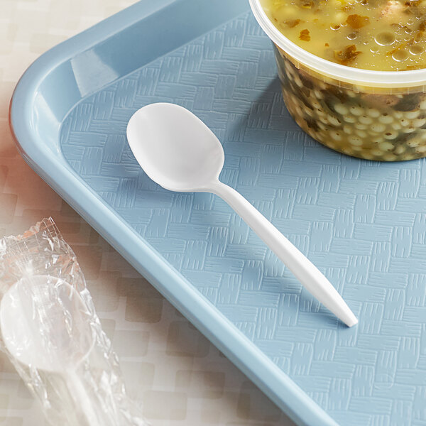 A white plastic Choice soup spoon next to a bowl of soup.