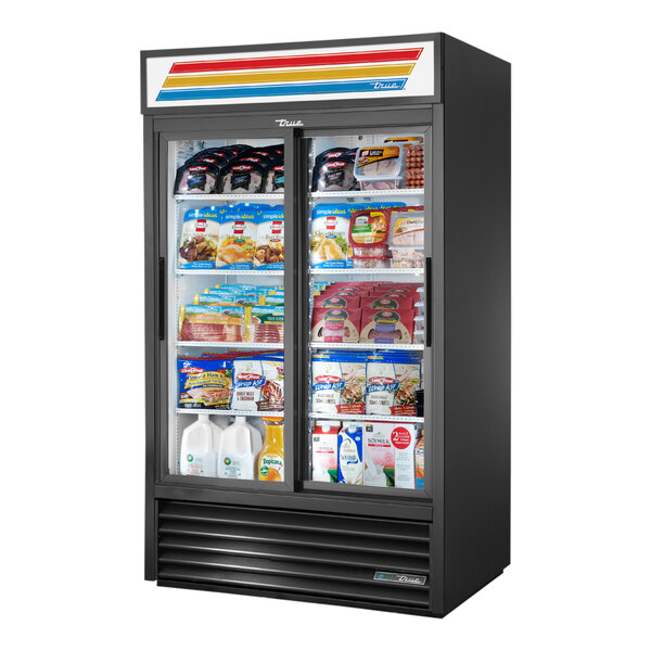A black True refrigerated merchandiser with glass doors and shelves full of various products.