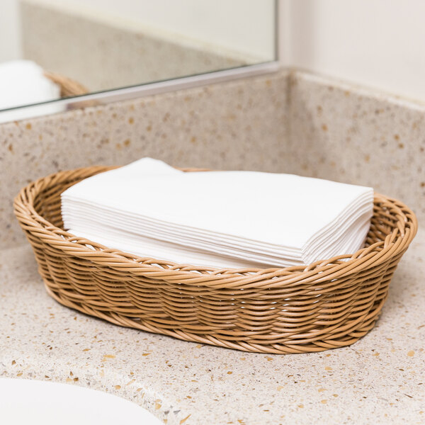 A wicker basket of Hoffmaster white linen-feel guest towels on a counter.