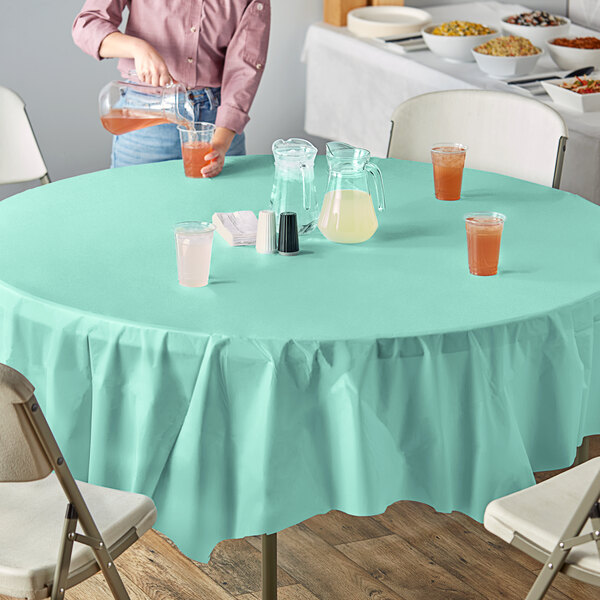 A table with a Fresh Mint Green OctyRound table cover and glasses of liquid.