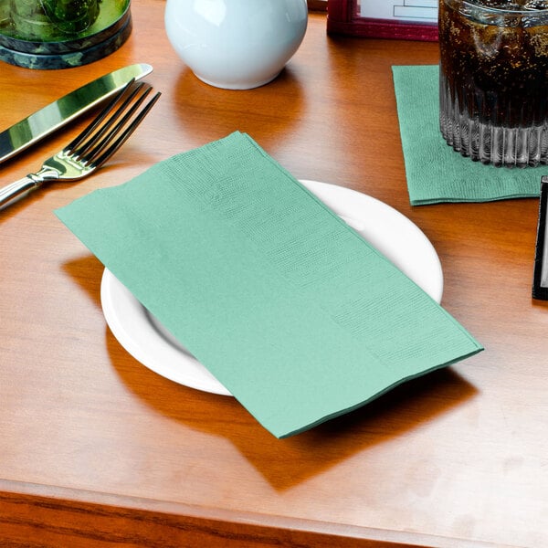 A plate with a Fresh Mint Green Creative Converting dinner napkin on it.