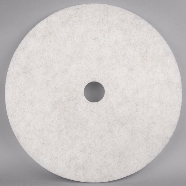 A white circular Scrubble floor pad with a hole in the middle.
