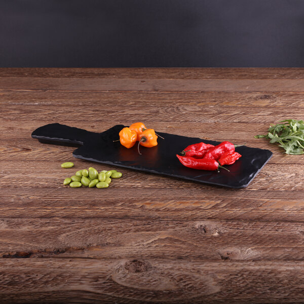 An Elite Global Solutions faux slate serving board with red and yellow peppers on it.