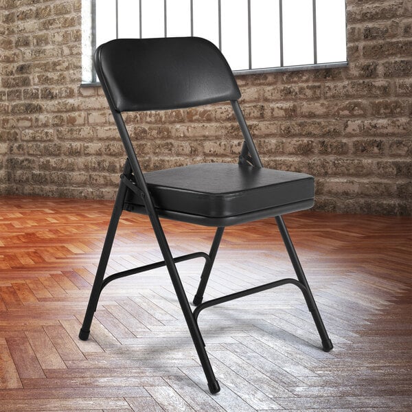 A black National Public Seating folding chair with black vinyl padding on the seat and back.