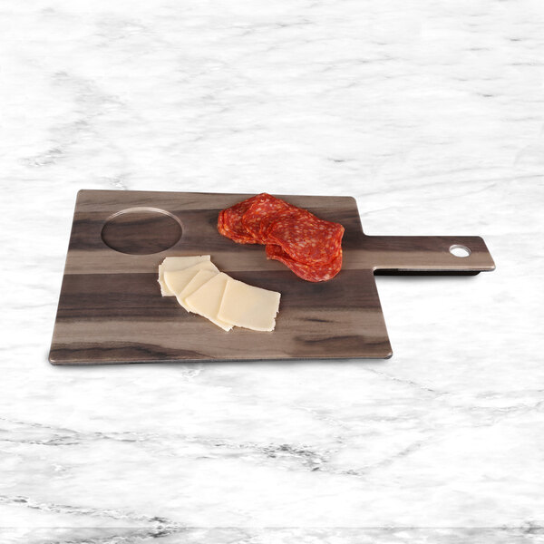 An Elite Global Solutions faux hickory wood melamine serving board with a ramekin compartment and meat and cheese on it.