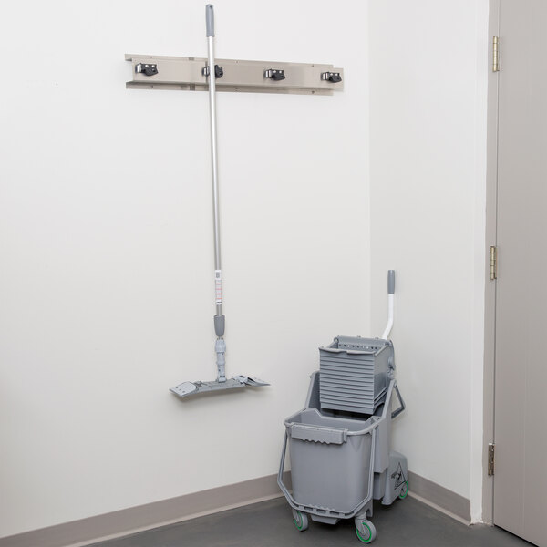 An Unger floor cleaning kit with a grey mop and bucket in the corner of a room.