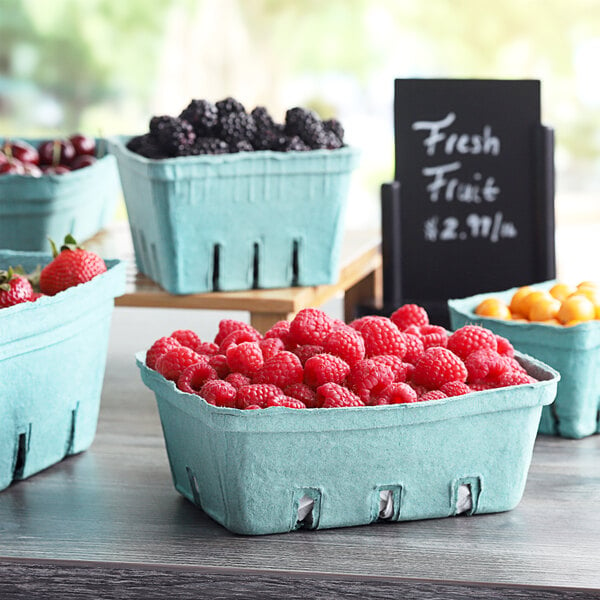 A table with green molded pulp baskets full of fresh fruit.
